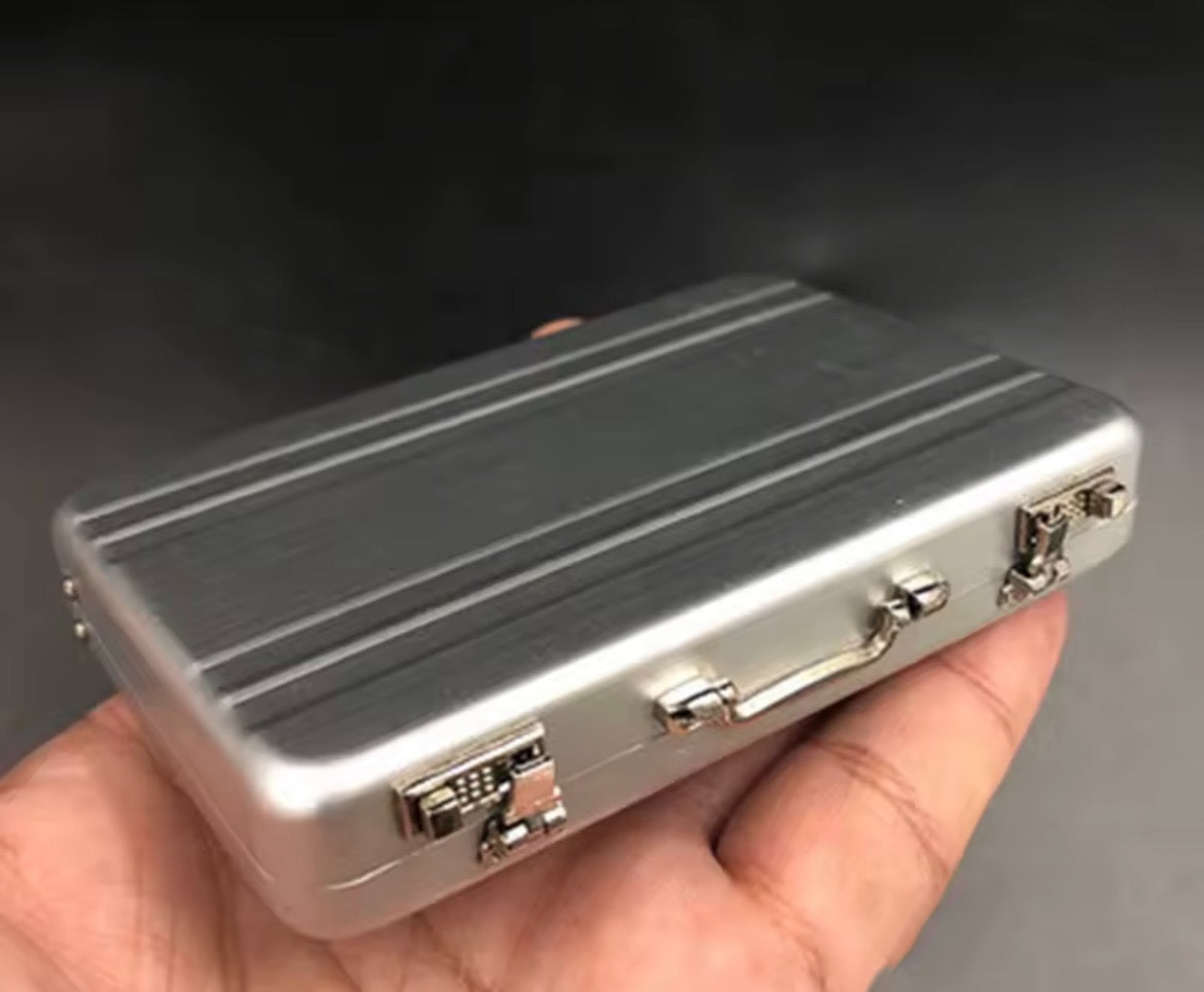 Silver Tiny Suitcase closed, held in one hand showing its palm-sized dimensions